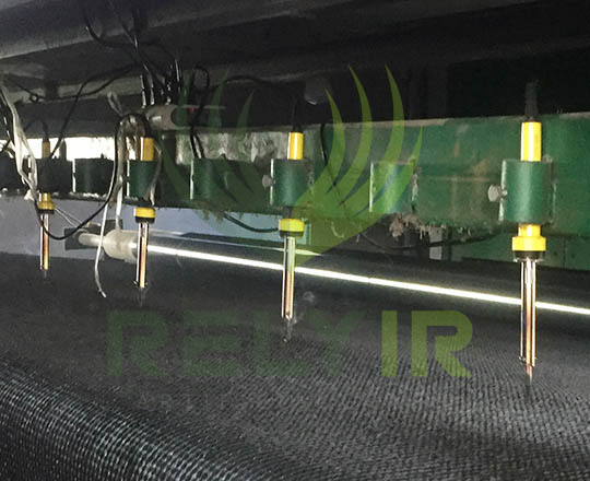 Perforating drainage holes into artificial grass backing