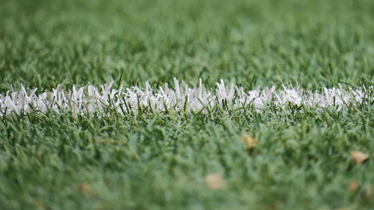 White line marking on green artificial turf close up