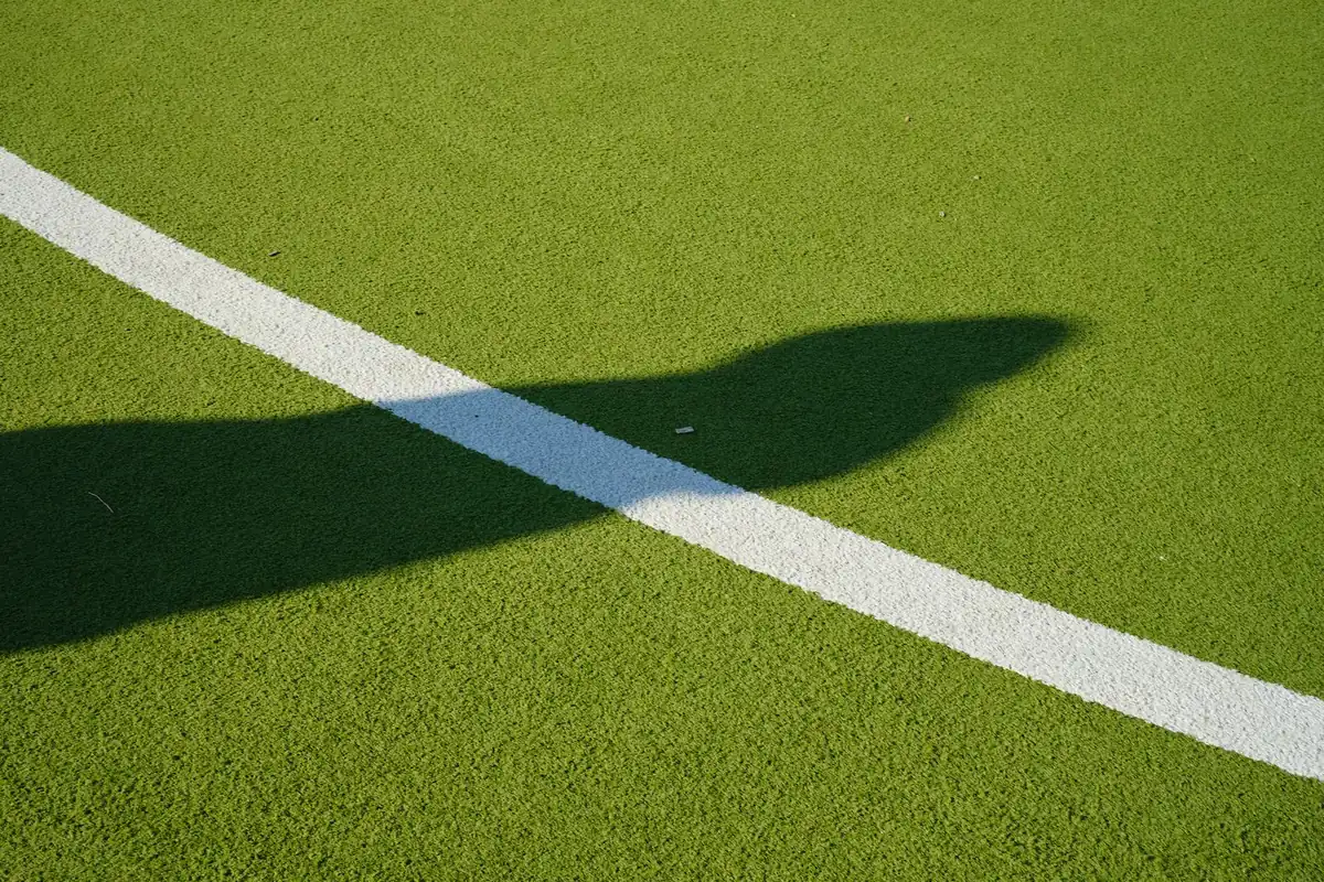Shadow cast over a white line on green artificial turf