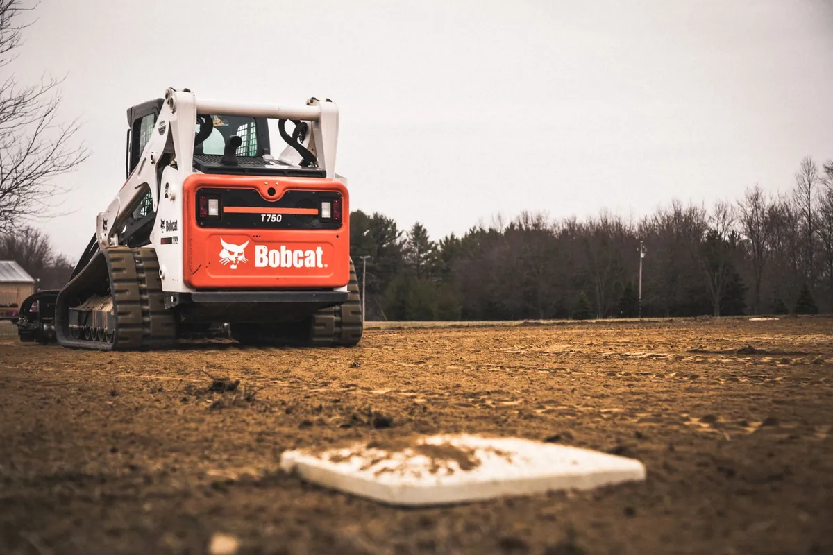 Skid loader working on a sports field surface