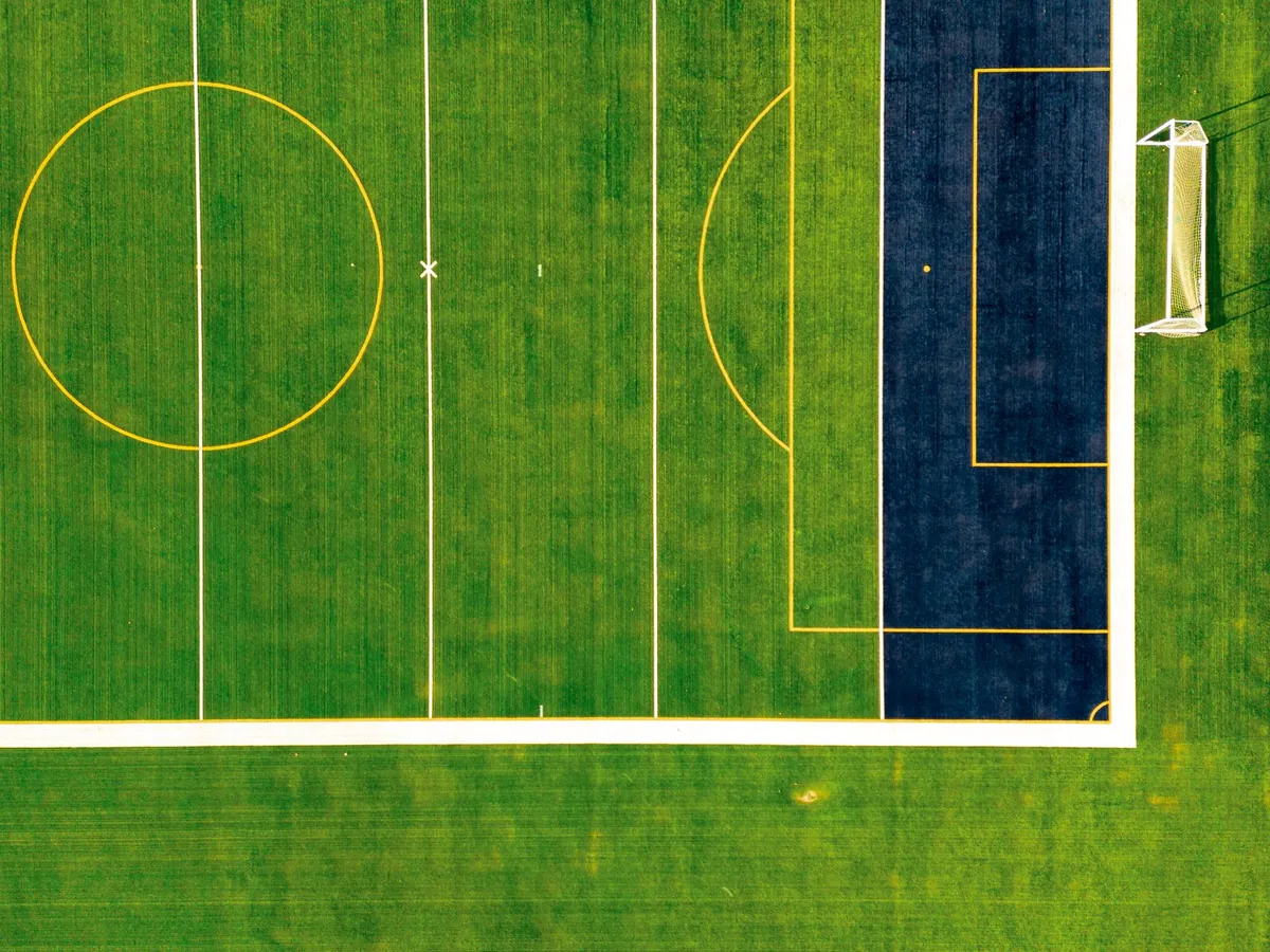 Wide green artificial turf surface seen from above in daylight