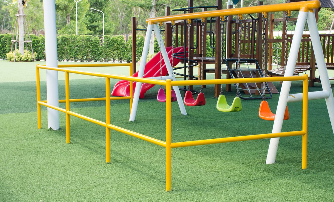 Children's playground with swings and slide set on artificial grass