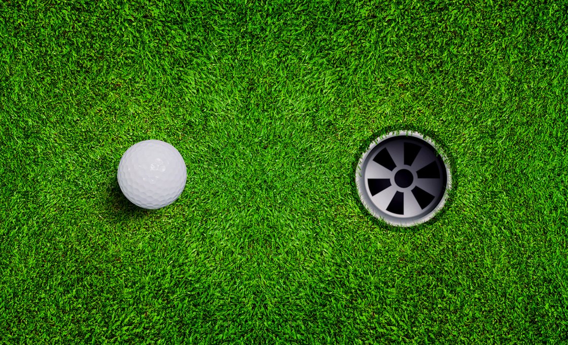 Golf ball beside a practice cup on a backyard putting green