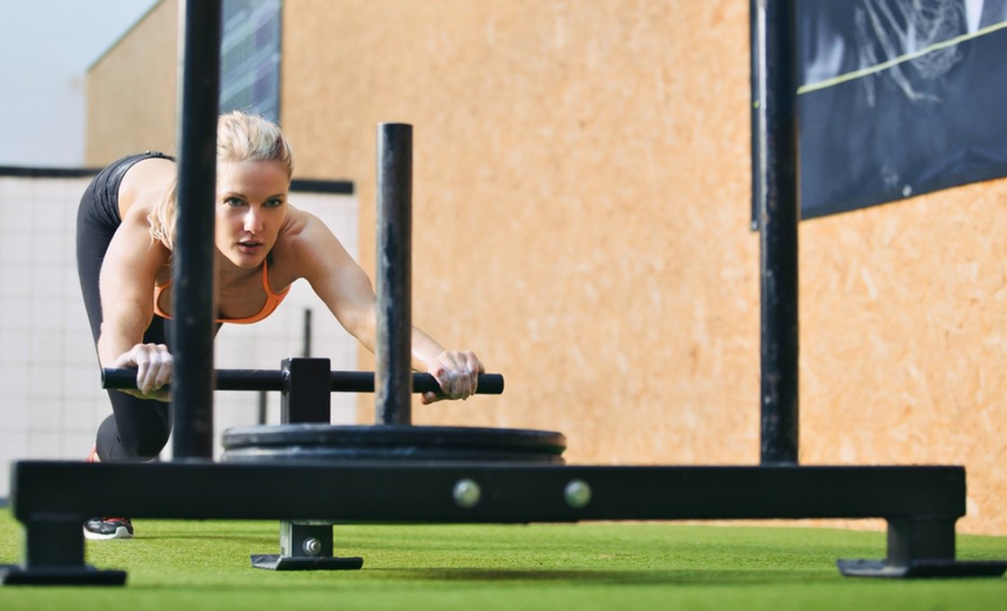 Athlete pushing a weighted sled on artificial grass track