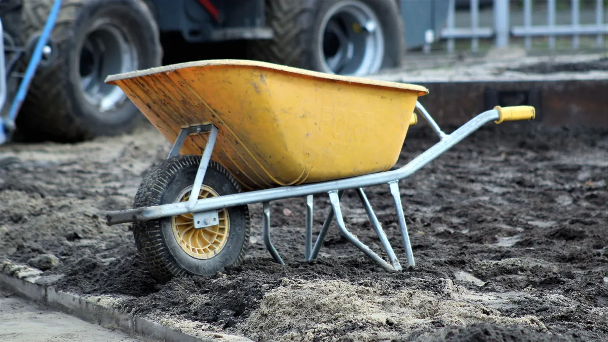 Yellow wheelbarrow on prepared dirt ground during site clearing
