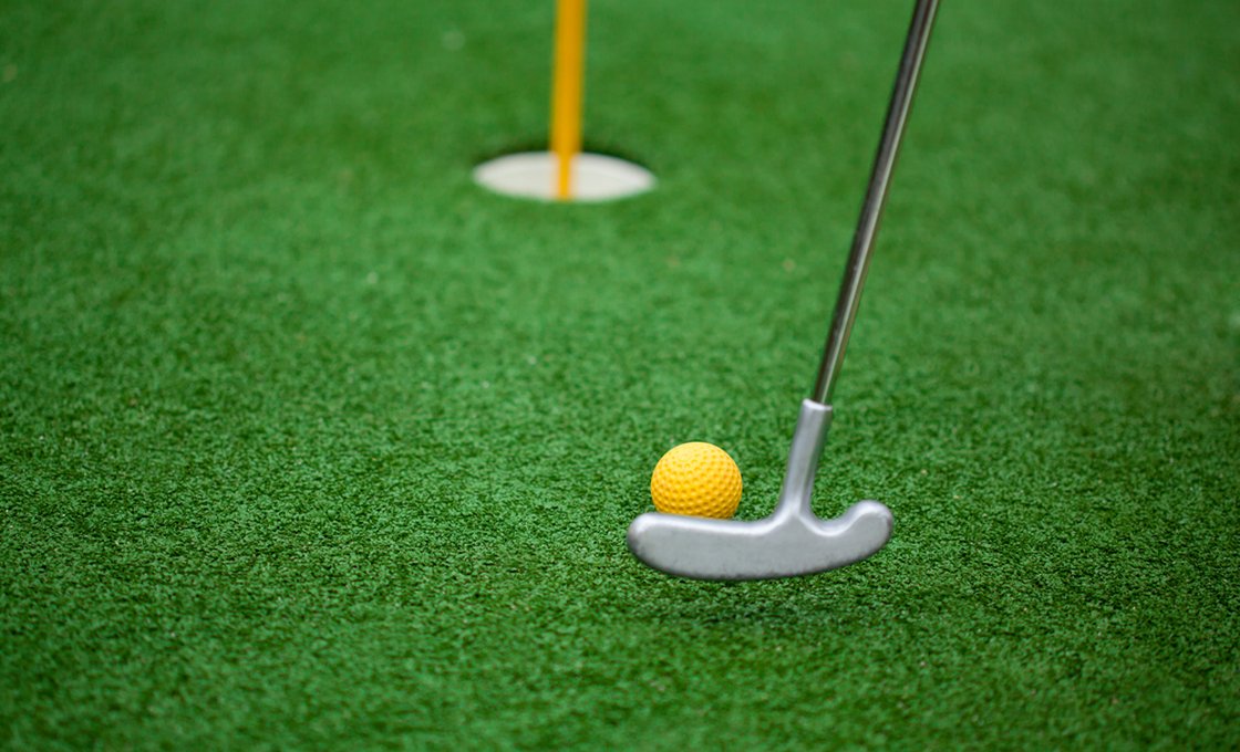Putter striking a ball toward the cup on a portable putting green