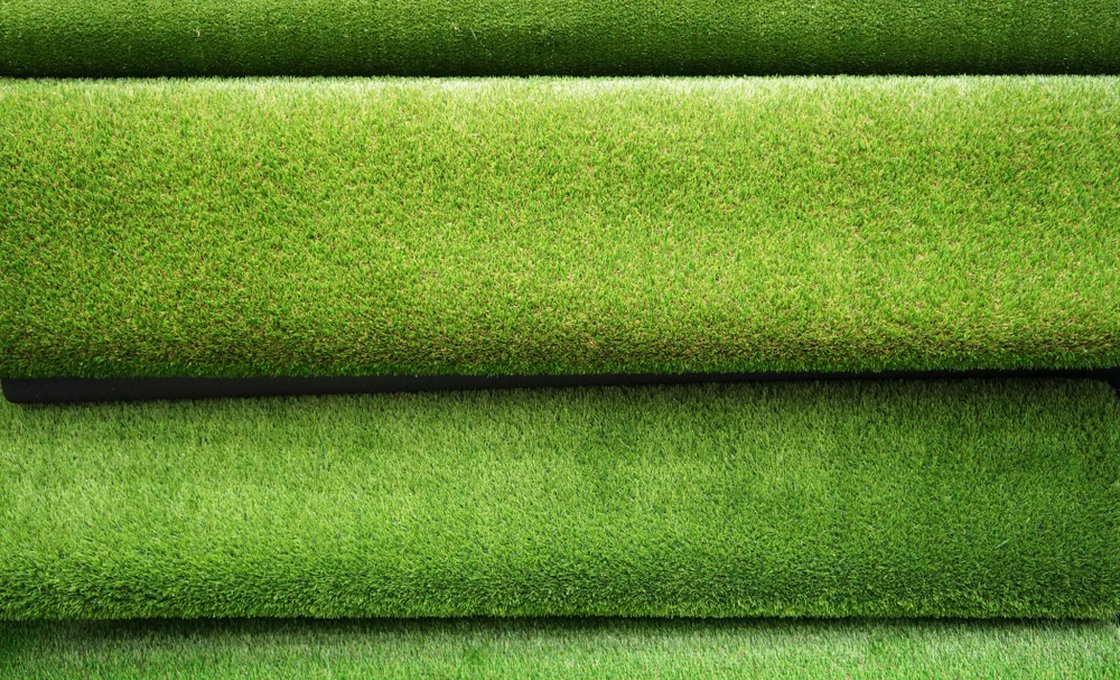 Tiered display of artificial grass rolls showing different pile heights across the product range