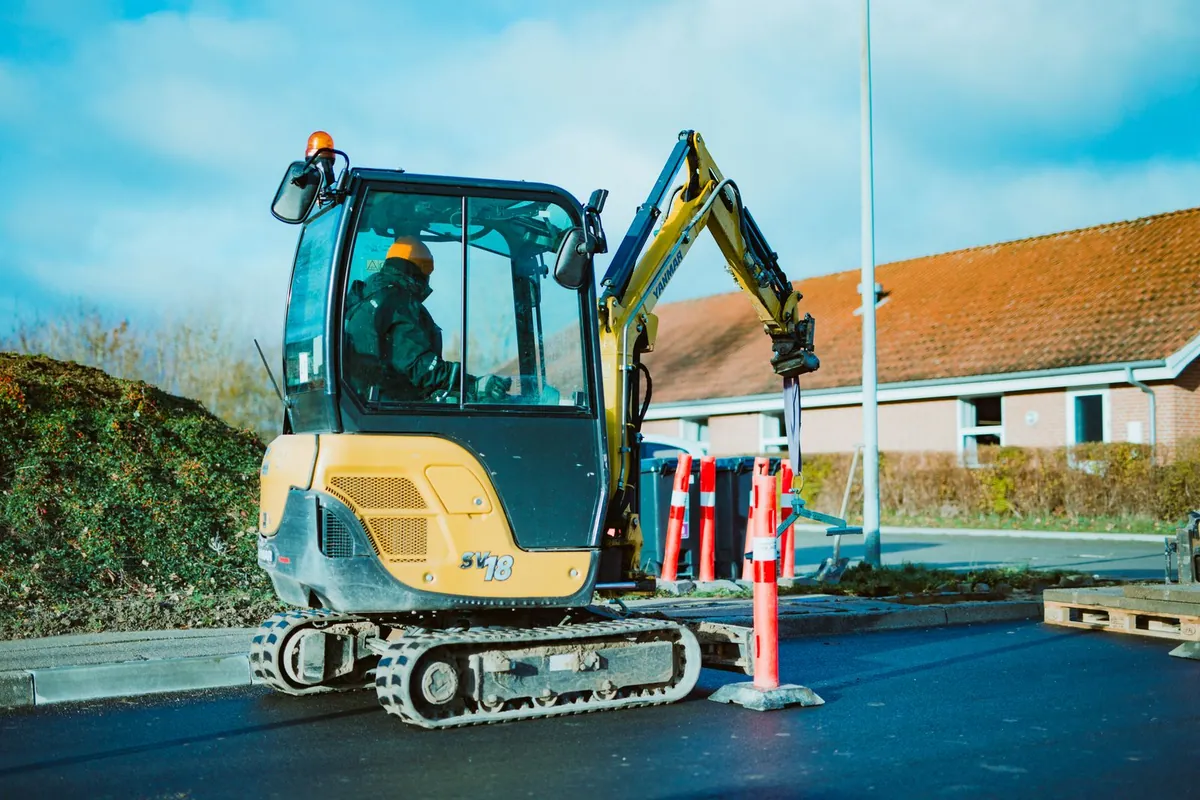 Mini excavator removing old lawn and loading spoil into a skip