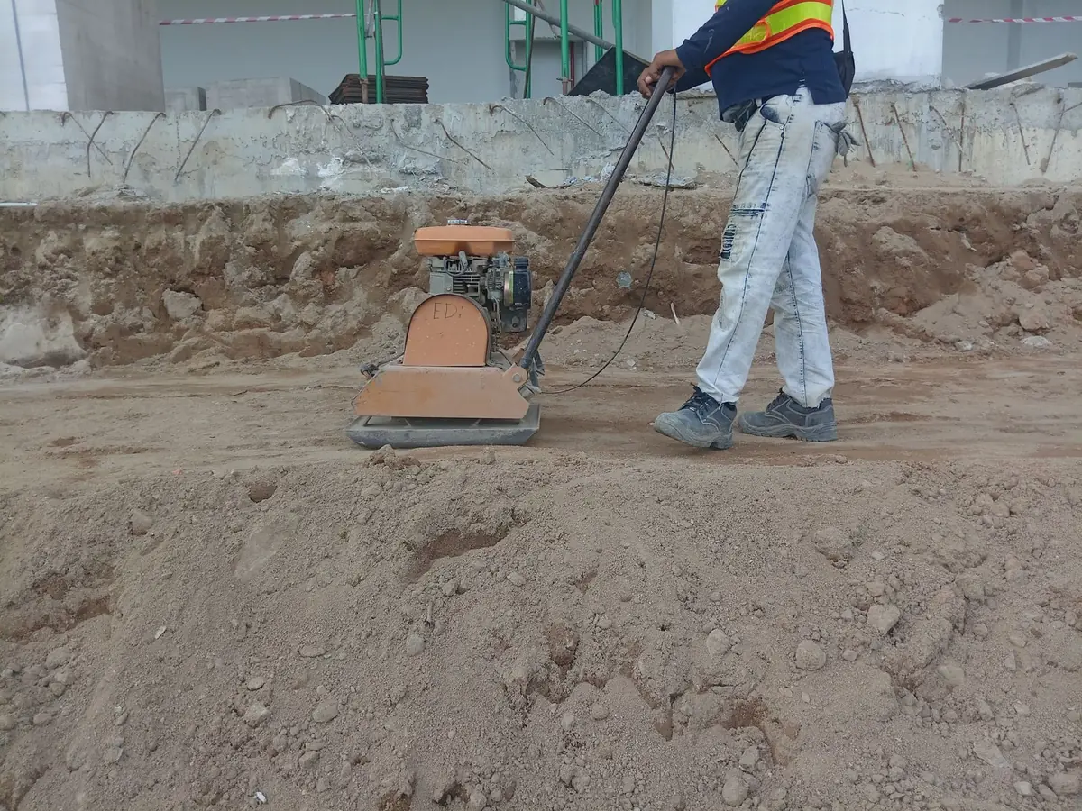 Homeowner operating a rented plate compactor over a prepared turf sub-base