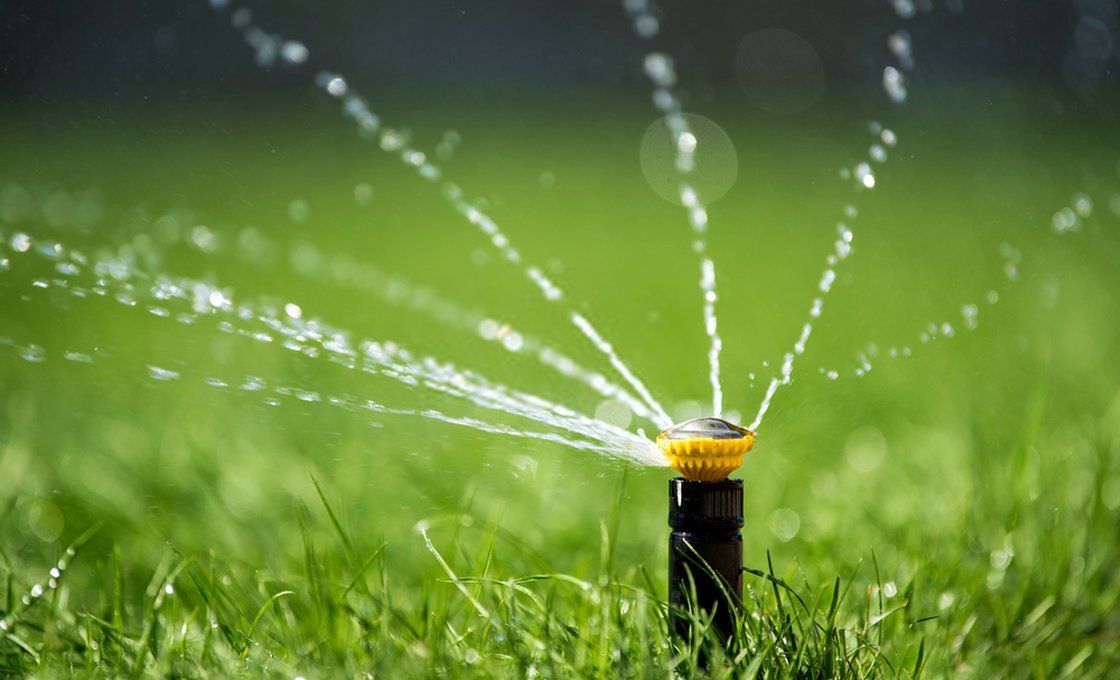 Water sprinkler on a lawn illustrating irrigation savings with artificial grass