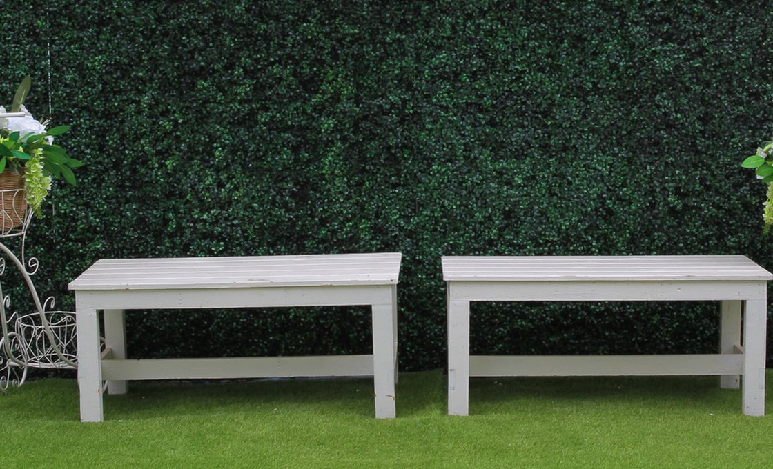 Garden benches set against an artificial grass hedge wall