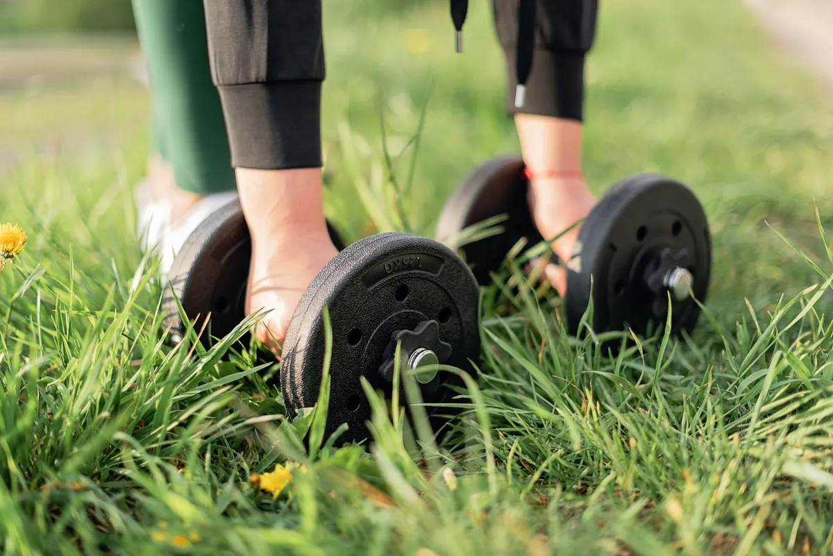 Person exercising with dumbbells on outdoor gym turf