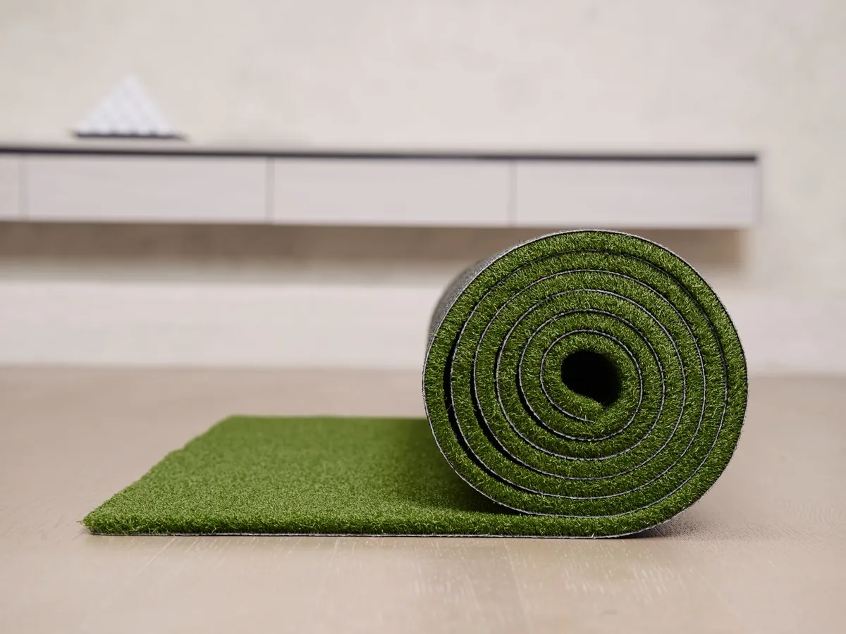 Rolled artificial turf mat showing the green pile face and darker backing edge