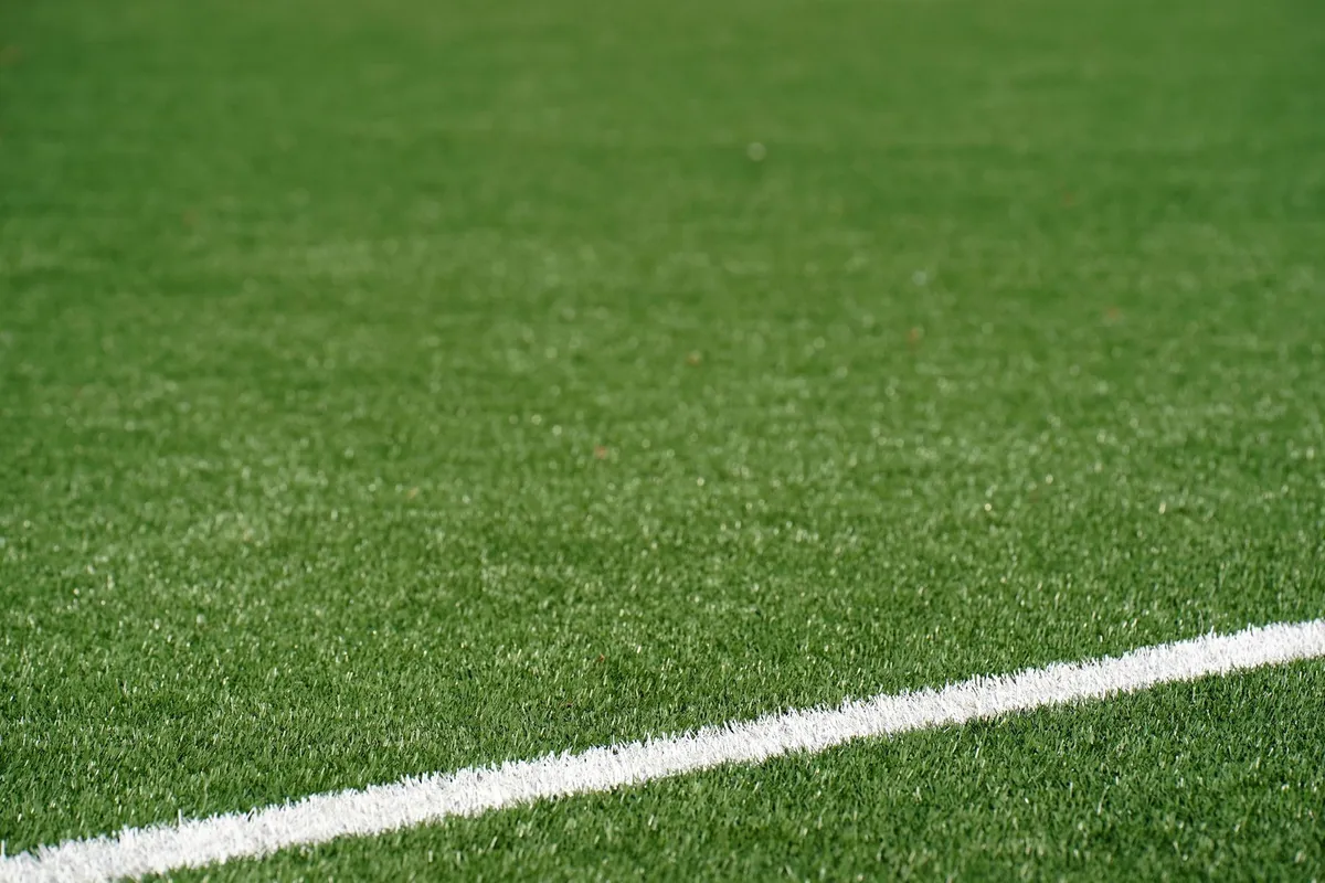 Green artificial soccer field with white boundary line