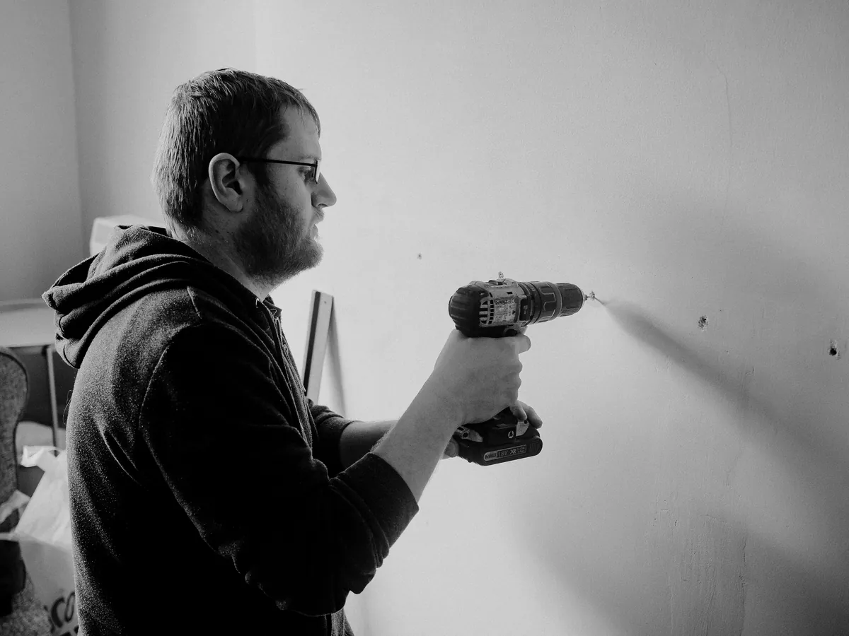 Man using a power drill to mount a wall fitting