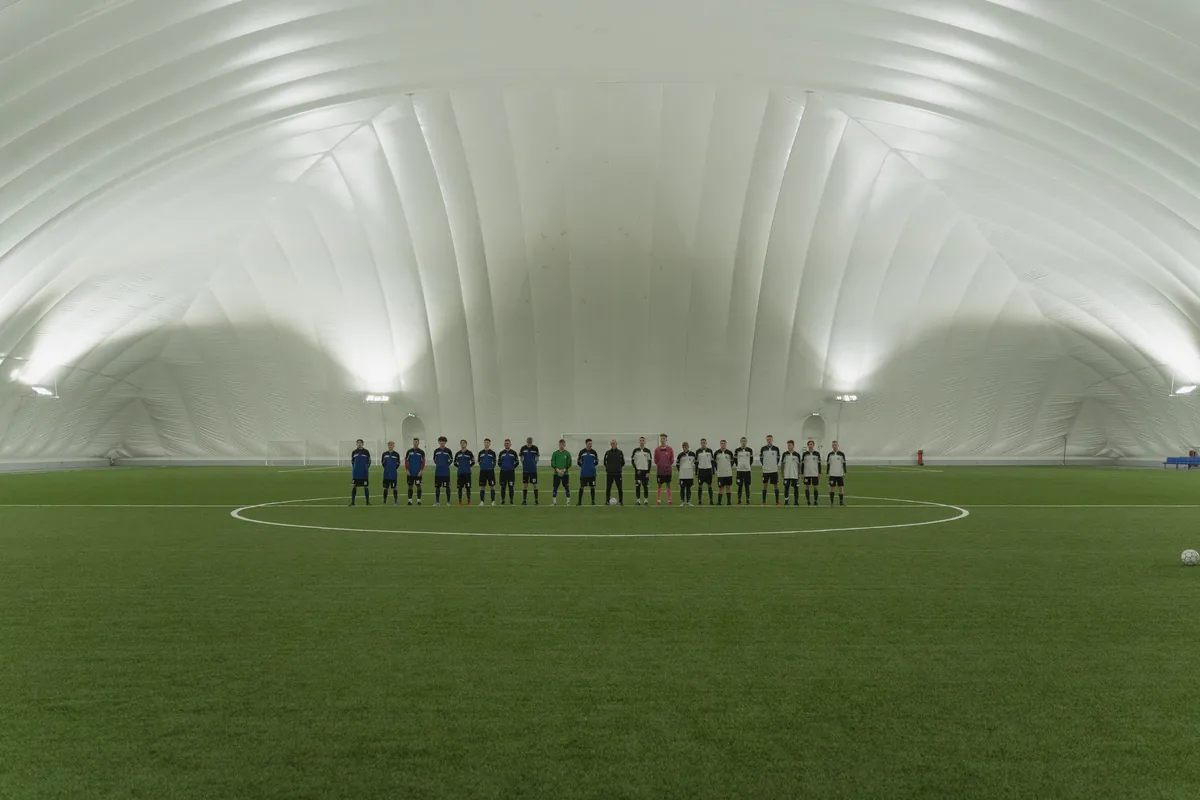 Two soccer teams lined up on an indoor turf field