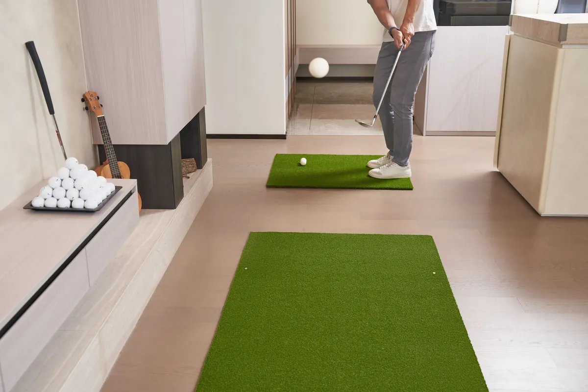 Golfer practicing putting indoors on artificial turf