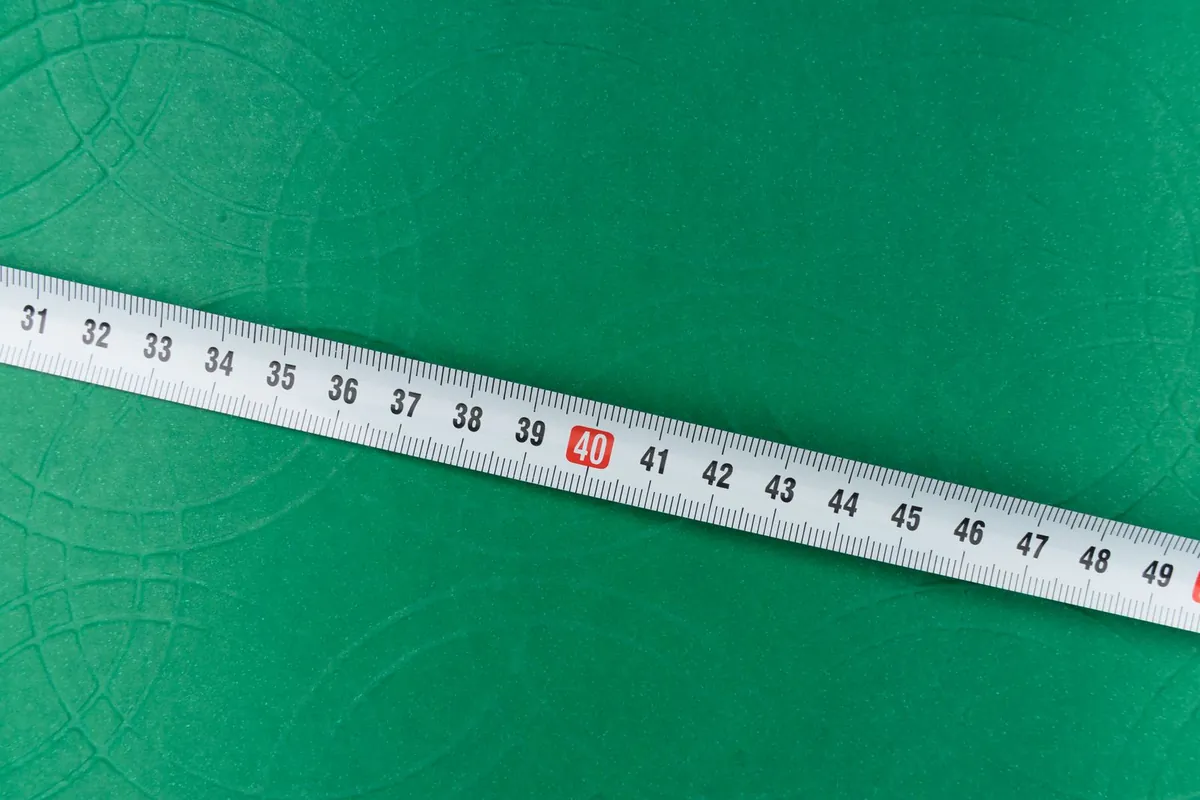 Tape measure laid diagonally across a green grass surface