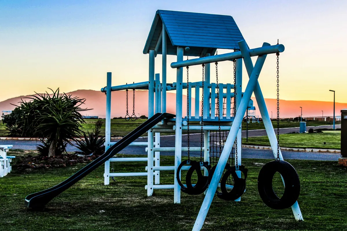 Outdoor playground with swings and slide in the evening