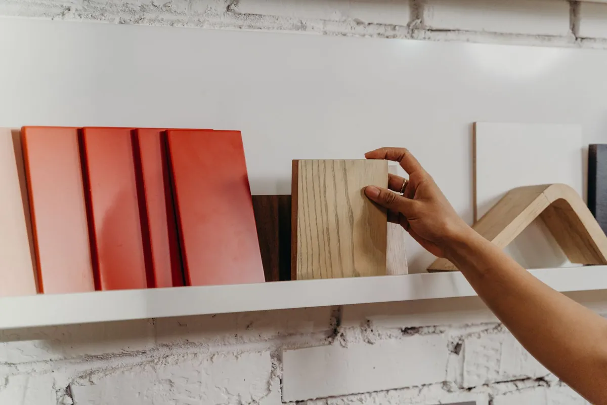 A hand selecting a material sample from a display shelf