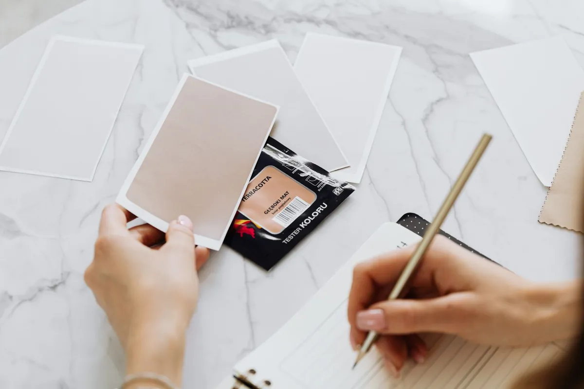 A person comparing colour samples beside a notebook
