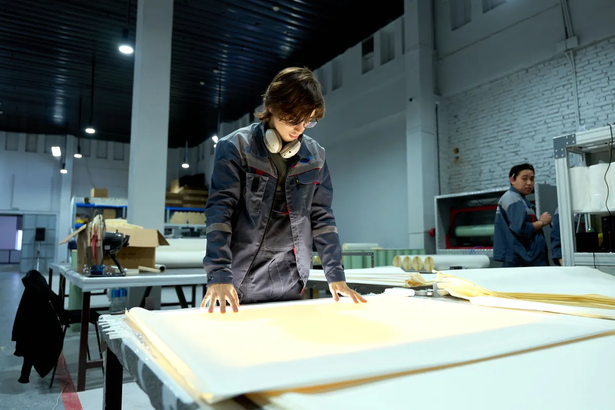 Trabajador examinando hojas de material en una fábrica