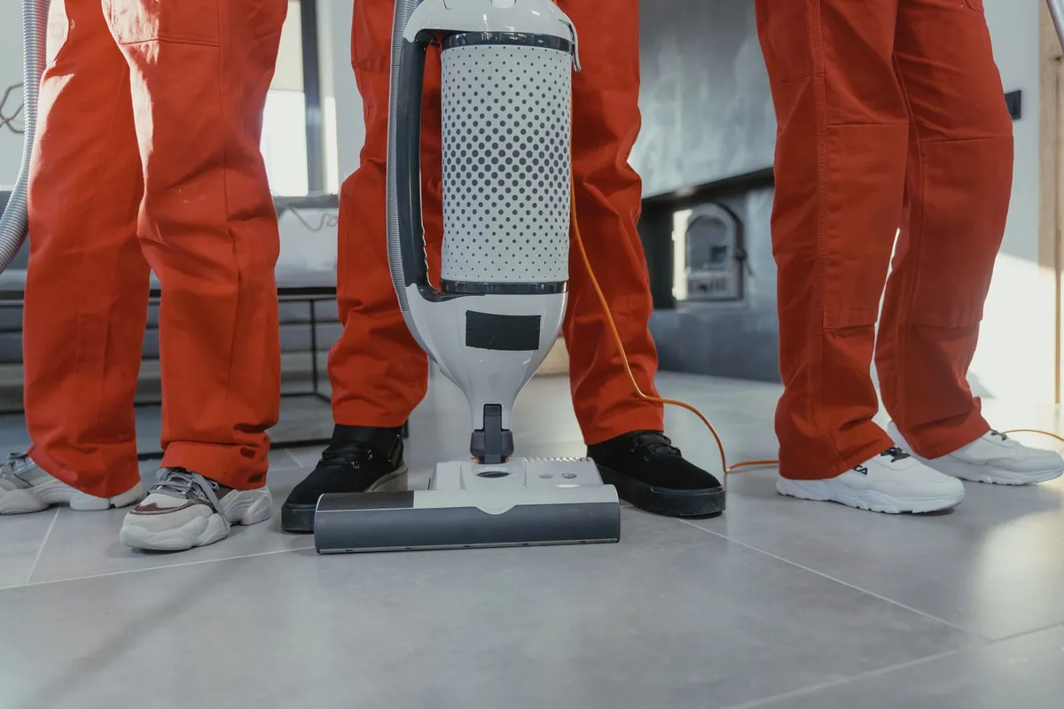 Team of professional cleaners using a vacuum cleaner indoors