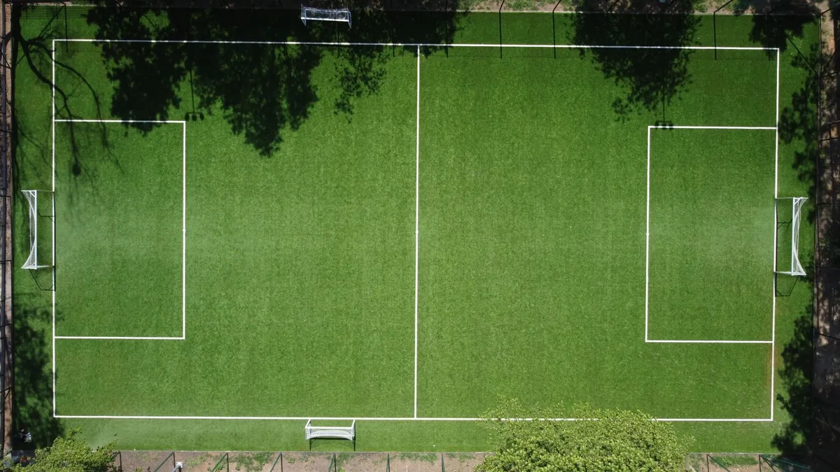 Green artificial turf field with white line markings in daylight