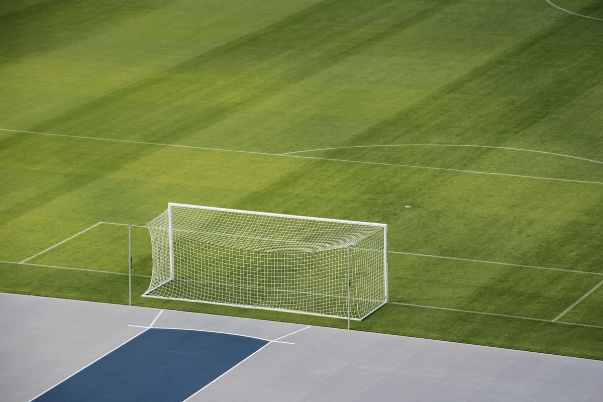 Aerial view of an empty soccer field showing the goal and green grass