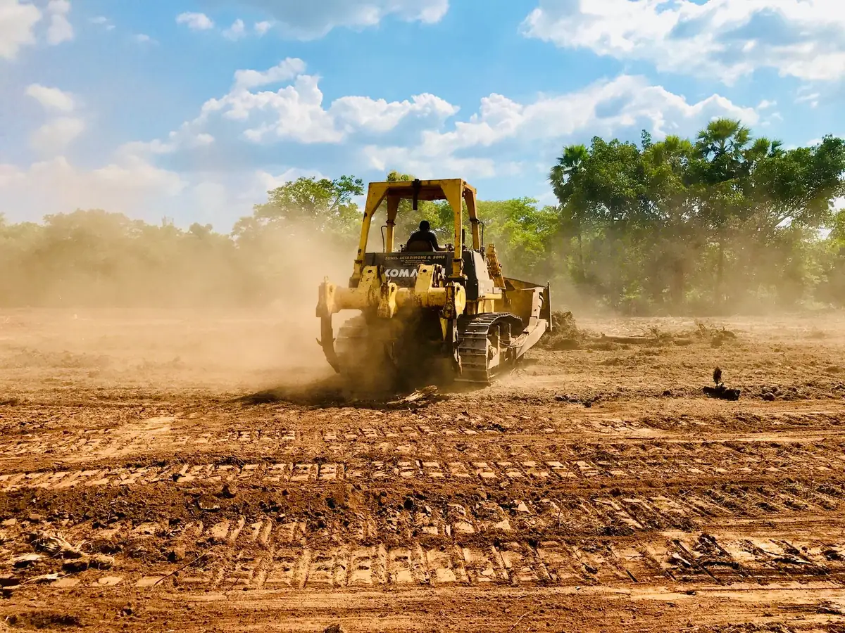 A yellow bulldozer moving earth during field site preparation