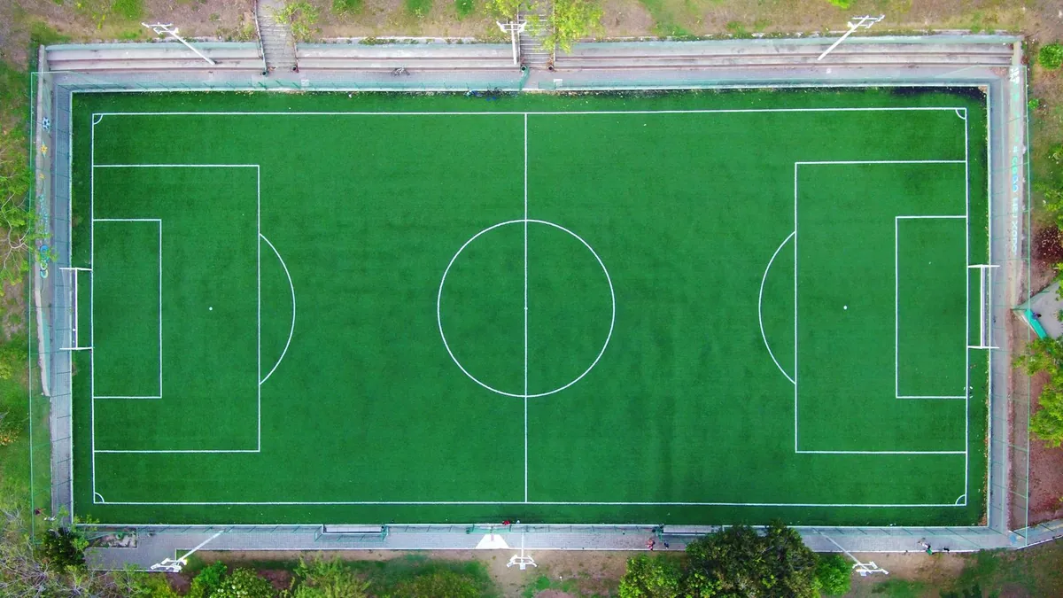 Aerial view of an empty green soccer field with white line markings