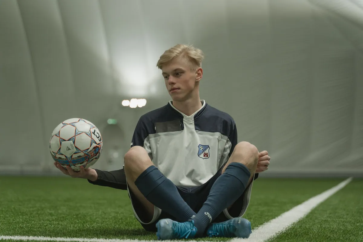 Teen player resting on indoor soccer turf with a ball