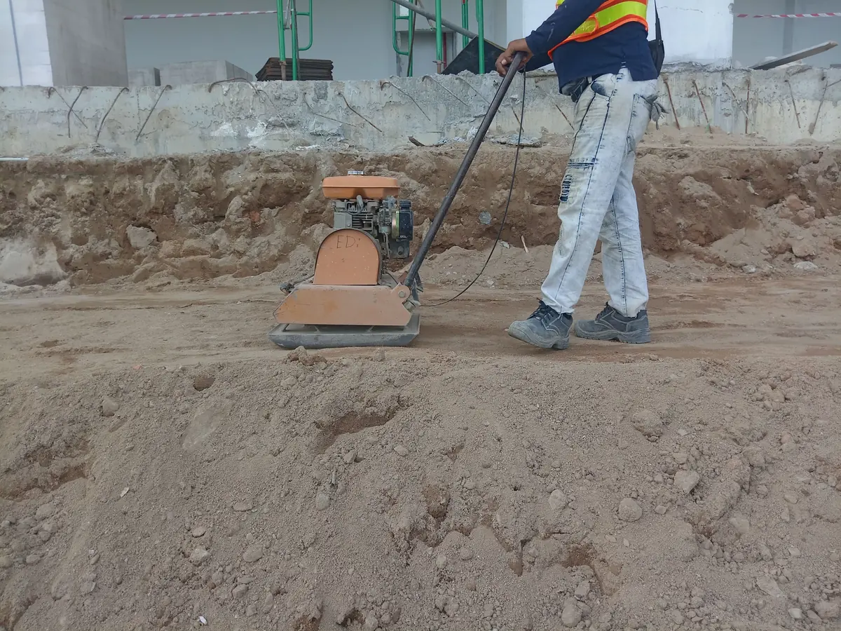 Construction worker compacting soil with a plate compactor