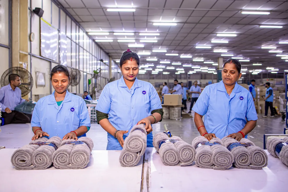 Workers inspecting rolled goods at a factory station
